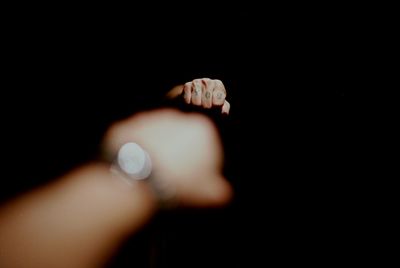 Cropped image of hand with tattoo reflecting on mirror in darkroom