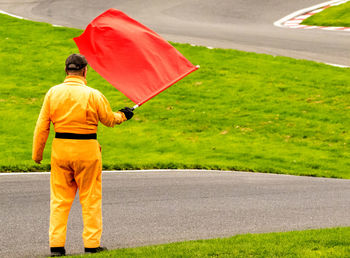 Rear view of man with umbrella standing on road