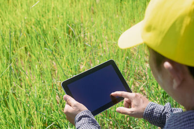 Midsection of man holding mobile phone in field