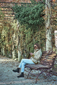 Young woman sitting on chair against plants