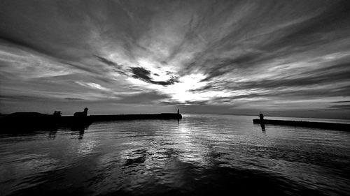 Silhouette man in lake against sky during sunset