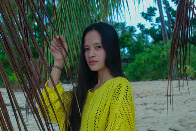 Portrait of young woman standing against trees