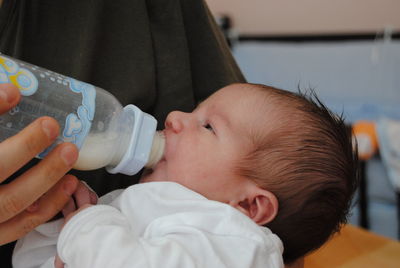 Midsection of mother feeding baby at home