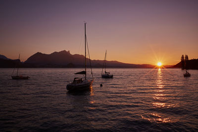 Silhouette sailboats in sea against sky during sunset