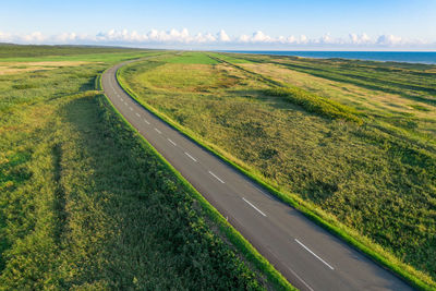 Road amidst field against sky