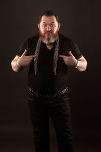 Portrait of man standing against black background