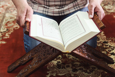 Midsection of man reading koran in mosque