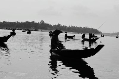 Silhouette men fishing on boat at lake