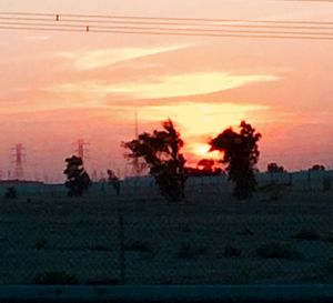 Scenic view of landscape against cloudy sky at sunset