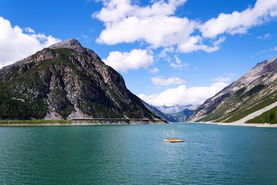 Pier with benches, livigno lake with corno brusadella mountain, italy