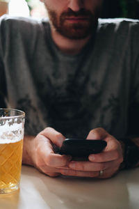 Midsection of man holding drink sitting on table