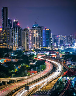 High angle view of illuminated street amidst buildings in city at night