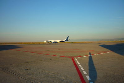 Airplane at airport runway against clear blue sky