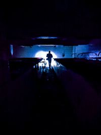 Rear view of silhouette man standing in illuminated tunnel