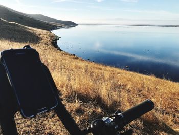 Scenic view of field by lake against sky