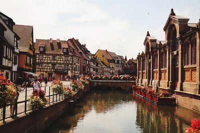 Canal amidst buildings in city against sky