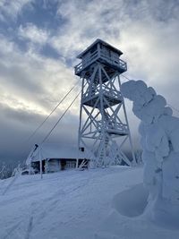 Traditional windmill on snow covered field against sky