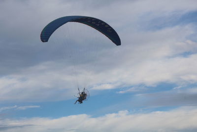 Low angle view of man paragliding against sky