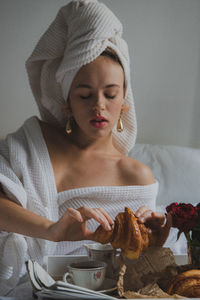 Young woman looking away while sitting on table