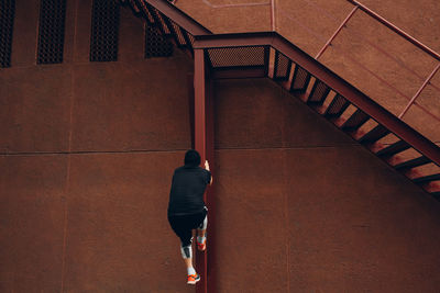 Rear view of woman walking on staircase against building