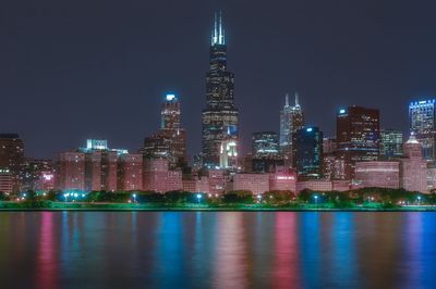 Illuminated urban skyline by lake michigan at night