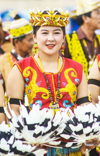 Portrait of smiling woman holding feathers while standing during festival