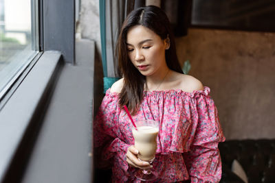 Woman holding cold coffee at cafe