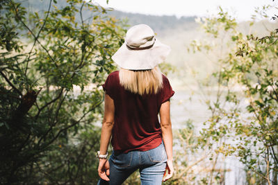 Rear view of woman wearing hat standing against trees