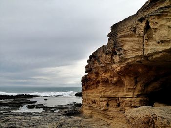 Rock formation on beach against sky