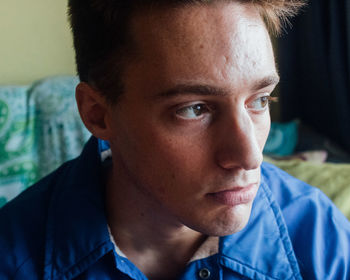 Close-up portrait of young man looking away at home