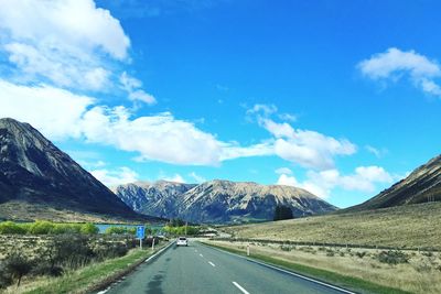 Road passing through mountains against cloudy sky