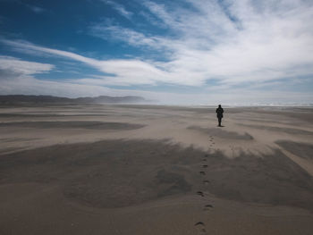 Man standing on sand dune in desert against sky