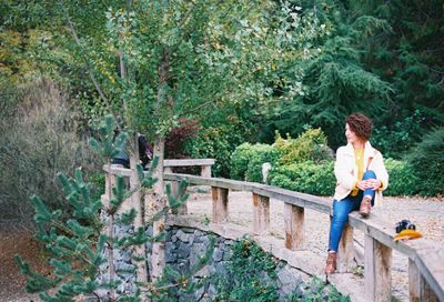 Full length of woman looking away while sitting on railing