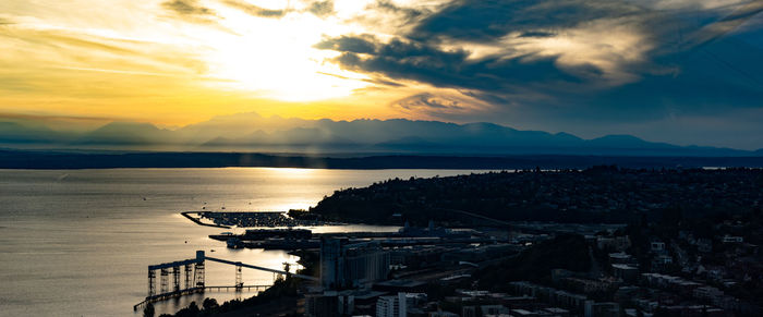 High angle view of sea and cityscape against sky during sunset