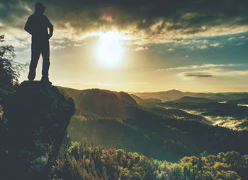 Moment of loneliness. man on the rock empires and watch over the misty landscape