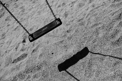 High angle view of empty swing with shadow on field