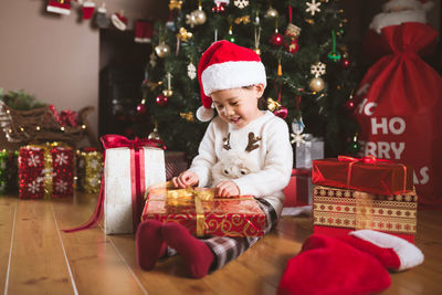 Young girl sit on floor and open christmas gift box at home