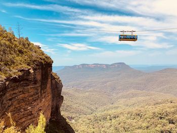 Low angle view of overhead cable car against mountains