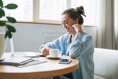 Young woman using mobile phone while sitting at home