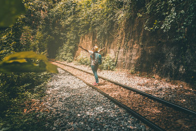 Rear view of man standing by railroad tracks in forest