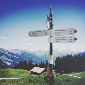 Directional sign on country road against mountains