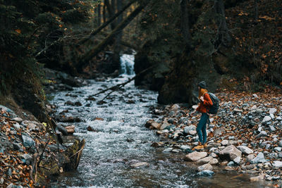 Woman walking by stream in forest