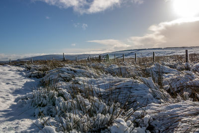 Scenic view of snow covered land against sky