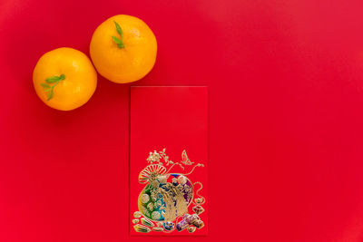 Close-up of orange fruits against red wall