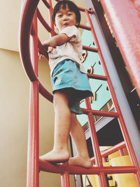 Low angle view of boy on slide in playground