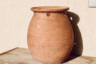 Close-up of vase on table against wall