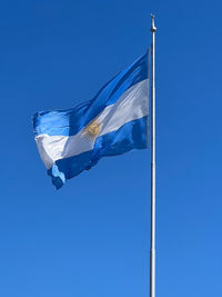 Low angle view of flag against clear blue sky