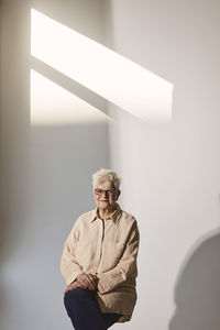 Smiling elderly woman sitting against white background