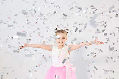 Portrait of smiling girl with arms raised standing in background