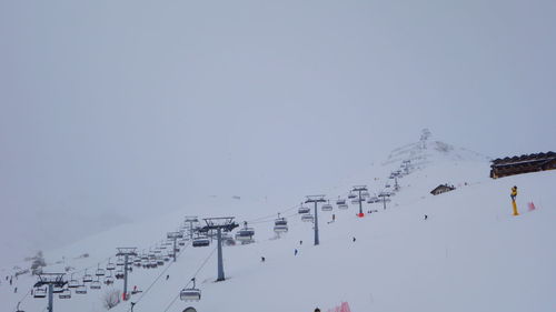 People skiing on snow covered mountain against sky